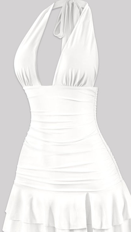 White halter mini dress with deep V neckline, ruched sides, and layered ruffle hem – flirty summer dress or bachelorette party outfit for women.
